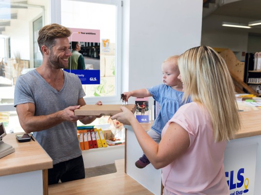 Een vrouw en haar kind halen een pakket op bij een GLS Parcel Shop