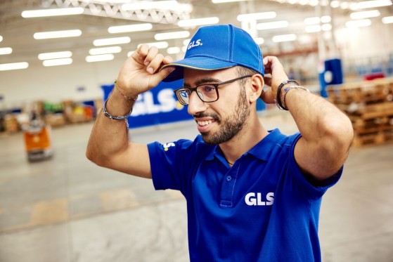 Een GLS-depotmedewerker zet zijn blauwe pet recht