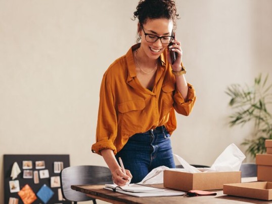Een vrouw aan de telefoon naast GLS pakjes
