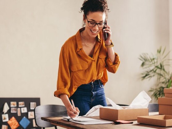 Een vrouw praat aan de telefoon naast haar GLS pakje