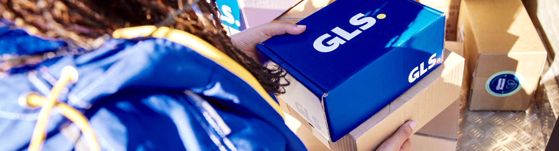 GLS-kuljettaja pitää käsissään paketteja